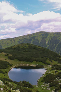 Scenic view of green landscape and lake against sky
