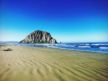 Scenic view of beach against clear blue sky