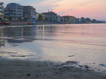 Scenic view of sea and buildings against sky during sunset