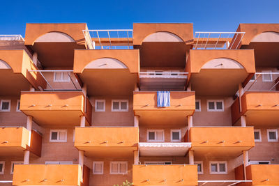 Facade of a block of holiday apartments on the beach, all with an outdoor balcony.