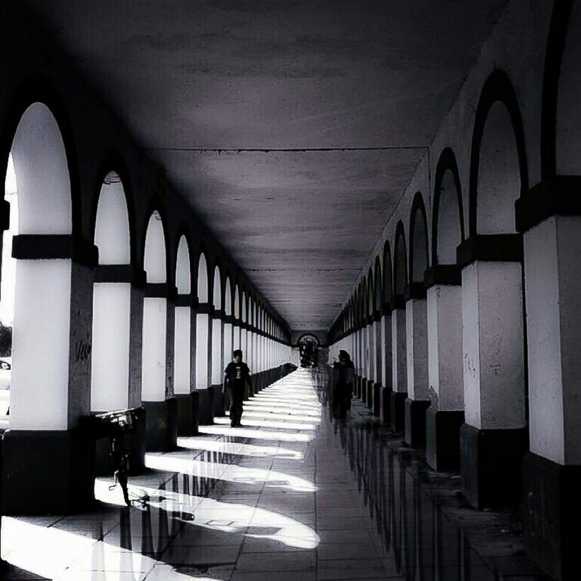 indoors, ceiling, the way forward, architecture, built structure, in a row, diminishing perspective, empty, corridor, railing, vanishing point, repetition, walking, incidental people, men, arch, day, sunlight, tiled floor