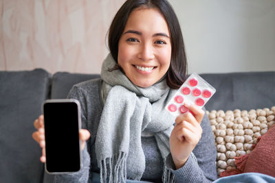 Portrait of young woman using mobile phone at home