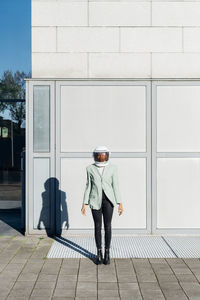 Businesswoman with astronaut helmet in front of office building