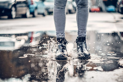 Low section of person standing on road in rain