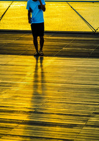 Low section of woman standing on yellow surface