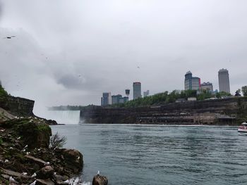 Scenic view of river by buildings against sky
