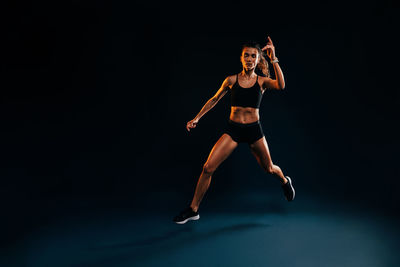 Female athlete jumping against black background