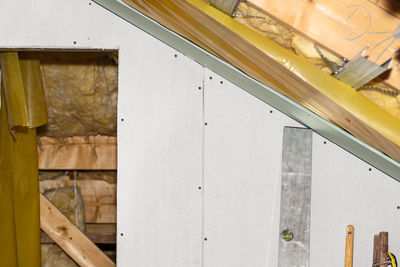 Mounted white plasterboards to an aluminum loft frame, visible yellow vapor barrier foil.