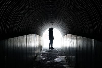 Rear view of silhouette man walking in tunnel