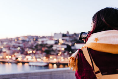 Woman in porto bridge taking pictures with camera at sunset. tourism in city europe. travel