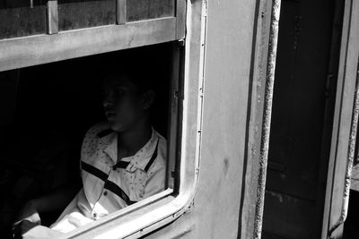 Young man sitting in train seen through window