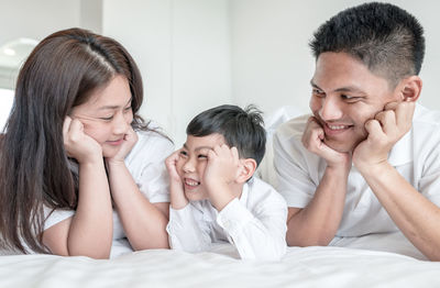 Parents with son relaxing on bed at home