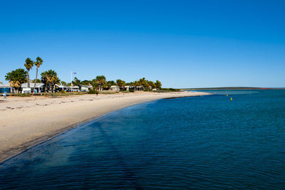 Scenic view of beach against clear blue sky