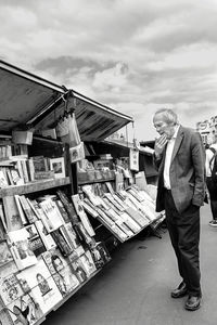 Man standing at market stall against sky