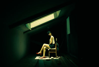 Man sitting on chair against wall at home