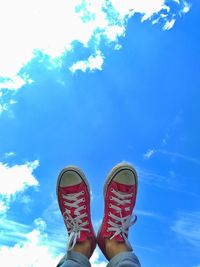 Low section of person with feet up against blue sky