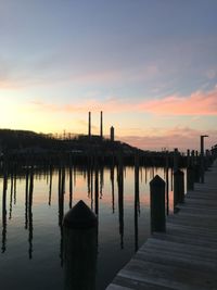 Wooden posts in factory against sky during sunset