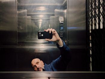 Man taking selfie of reflection in elevator