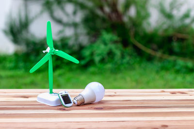 Close-up of light bulb with toy windmill on wooden table