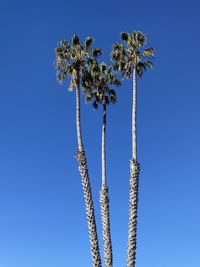 Low angle view of electricity pylon against clear blue sky