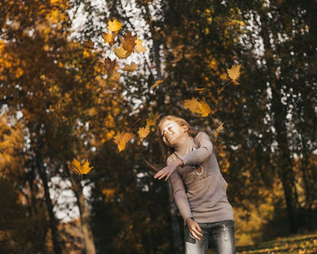 Teenage girl with freckles on a walk among yellow leaves in autumn autumn colors