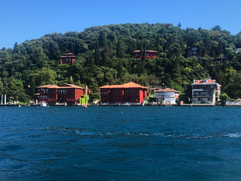 Houses by trees and buildings against clear sky