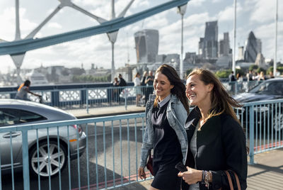 Uk, london, two happy women walking on the tower bridge