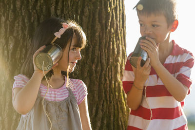 Little boy and girl playing with tin can phone in nature