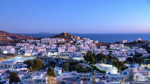 High angle view of townscape by sea against clear blue sky