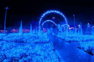 Illuminated christmas lights against blue sky at night