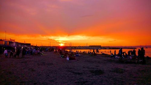 People on beach against sky during sunset