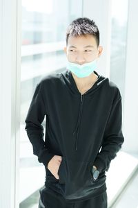 Young man looking away standing by window