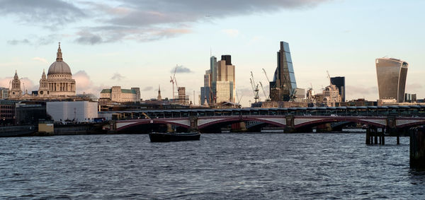 Bridge over river in city against sky