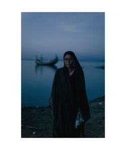 Portrait of smiling young woman standing against sea