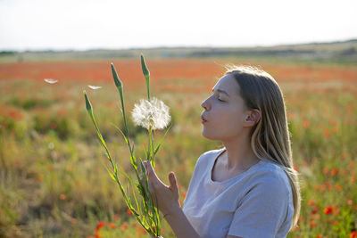 Portrait of young woman standing by plants on field