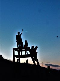 Silhouette men standing against clear sky during sunset