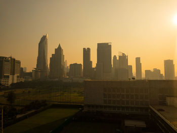 Modern buildings in city against sky during sunset