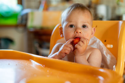 Portrait of cute baby girl eating fruit