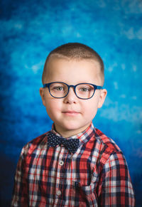 Portrait of boy wearing eyeglasses against blue background 