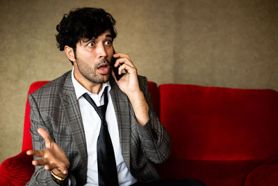 Young man using mobile phone while sitting on sofa