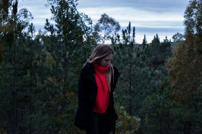 Young woman standing against trees in forest