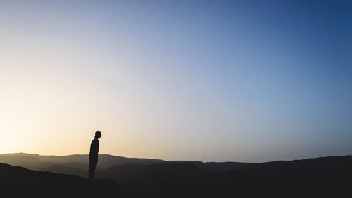 Silhouette man standing on mountain against clear sky