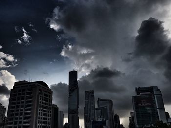 Low angle view of skyscrapers against cloudy sky