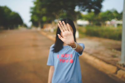 Young woman covering face with hand while standing on road