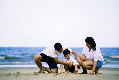 People on beach against clear sky