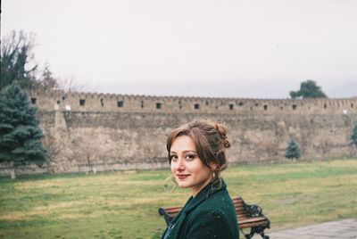Portrait of smiling beautiful woman against castle