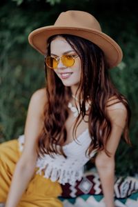 Portrait of young woman wearing sunglasses against plants