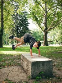 Boy doing handstand on bench at park