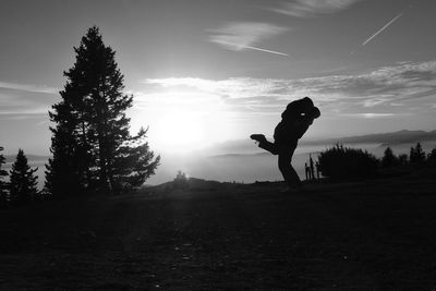 Silhouette of people standing on field at sunset