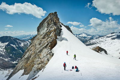 People on snowcapped mountain against sky